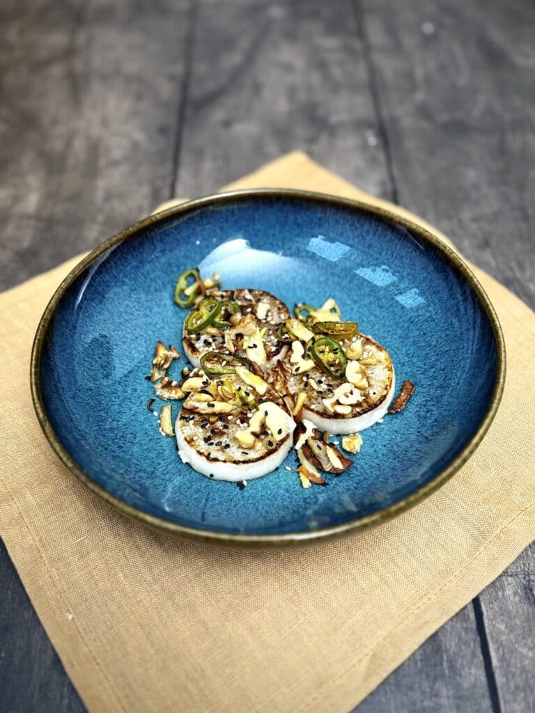 Roasted white radish with chili, garlic and nuts, topped with sesame seeds, side view
