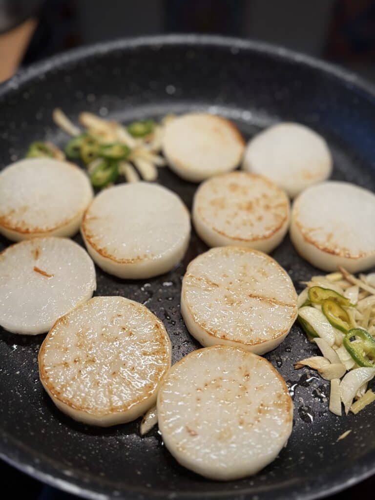 Sliced roasted white radish with chili and garlic in a pan