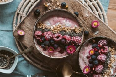 Delicious smoothie bowls topped with fresh berries, chia seeds, and granola on a rustic wooden table.