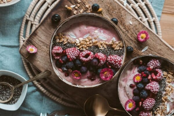 Delicious smoothie bowls topped with fresh berries, chia seeds, and granola on a rustic wooden table.