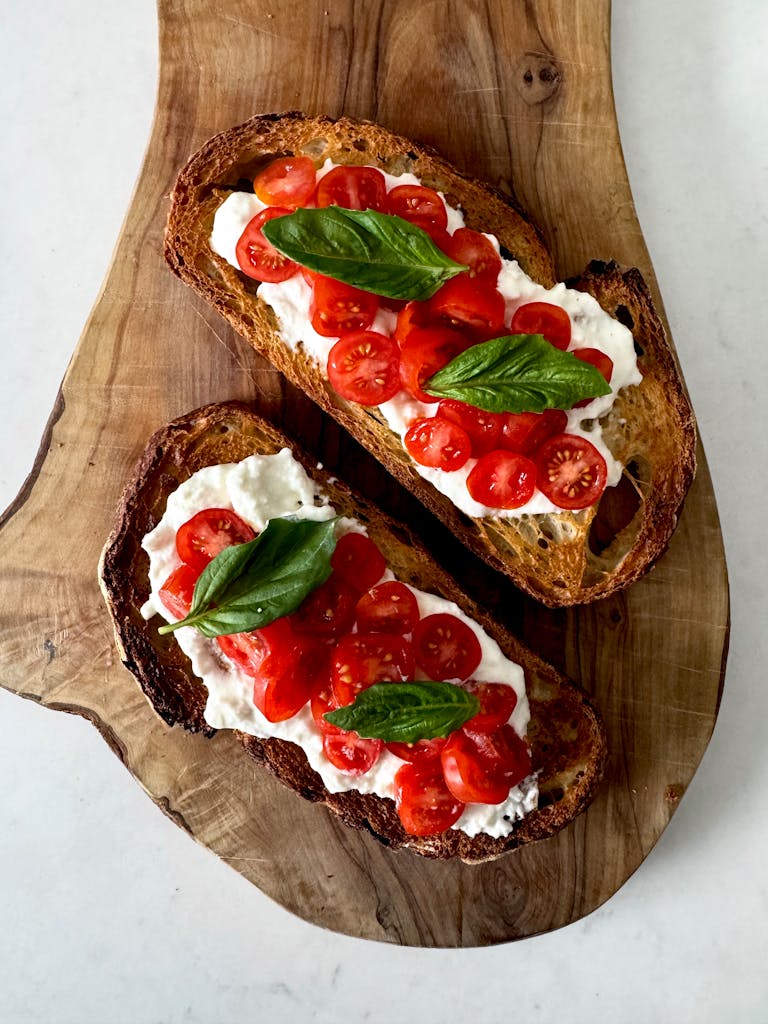 Fresh tomato bruschetta with basil leaves on rustic wooden board.