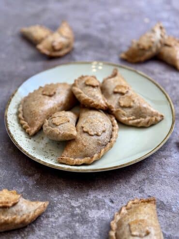 Side angle of oven-baked wholemeal empanadas with crisp golden crust.