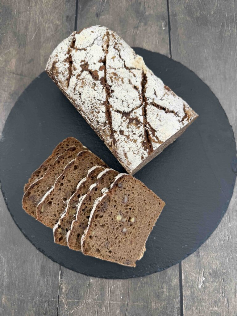 sliced wholegrain rye sourdough loaf with walnuts showing a moist crumb