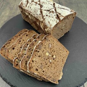 wholegrain rye sourdough bread with beetroot juice and walnuts sliced on a serving board